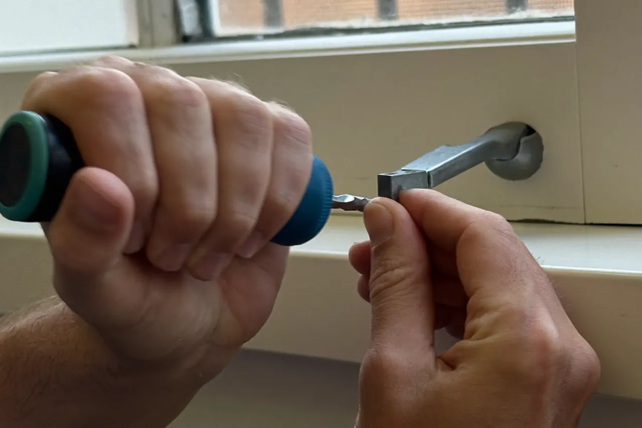 Craftsman repainting a timber window frame with a fine brush