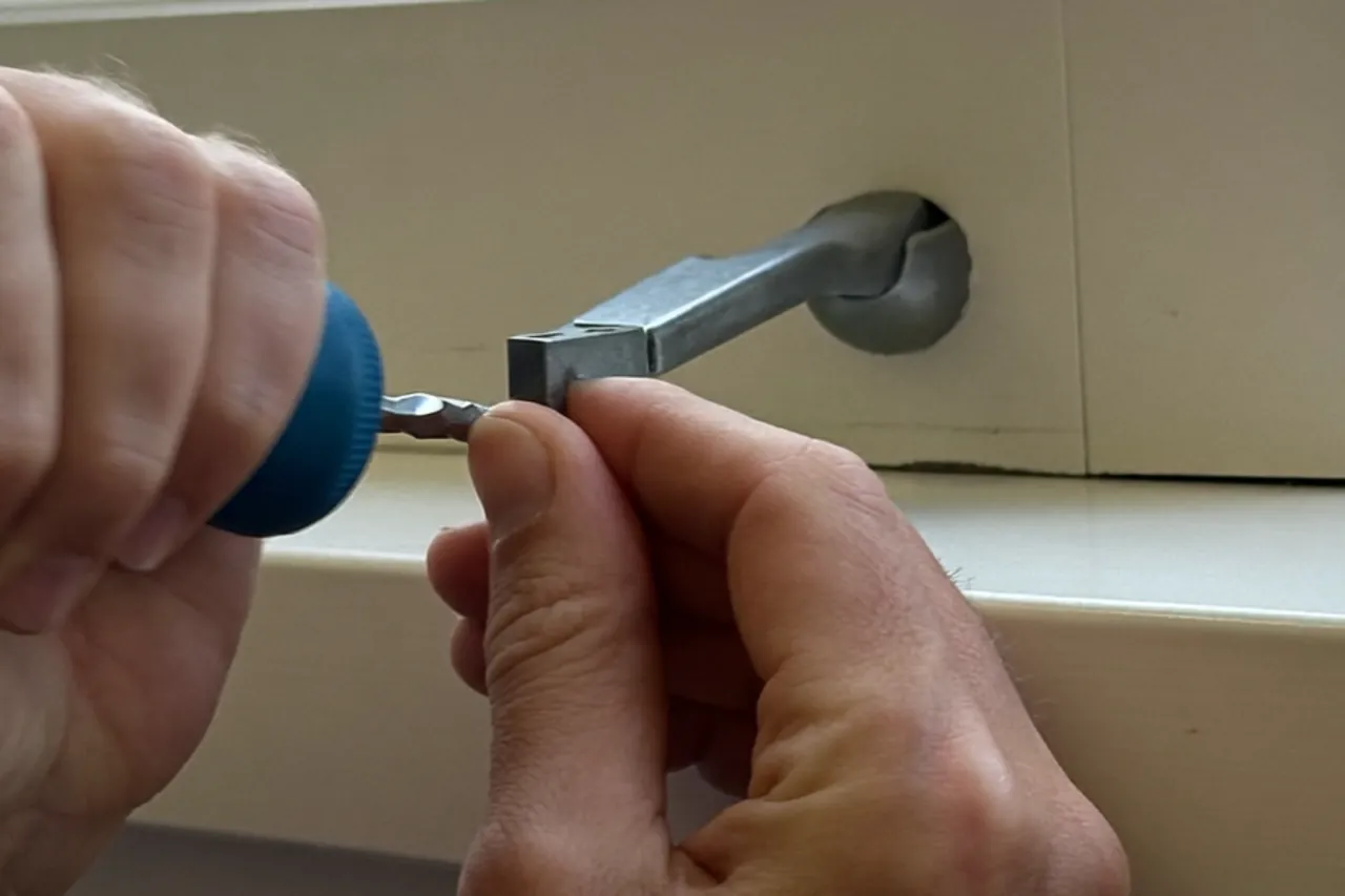 Installer fitting a new espagnolette handle to a window