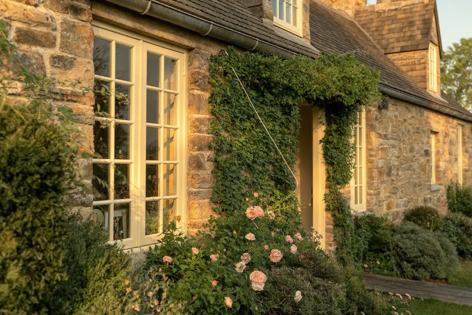 Period cottage with immaculate timber-look windows in golden-hour light