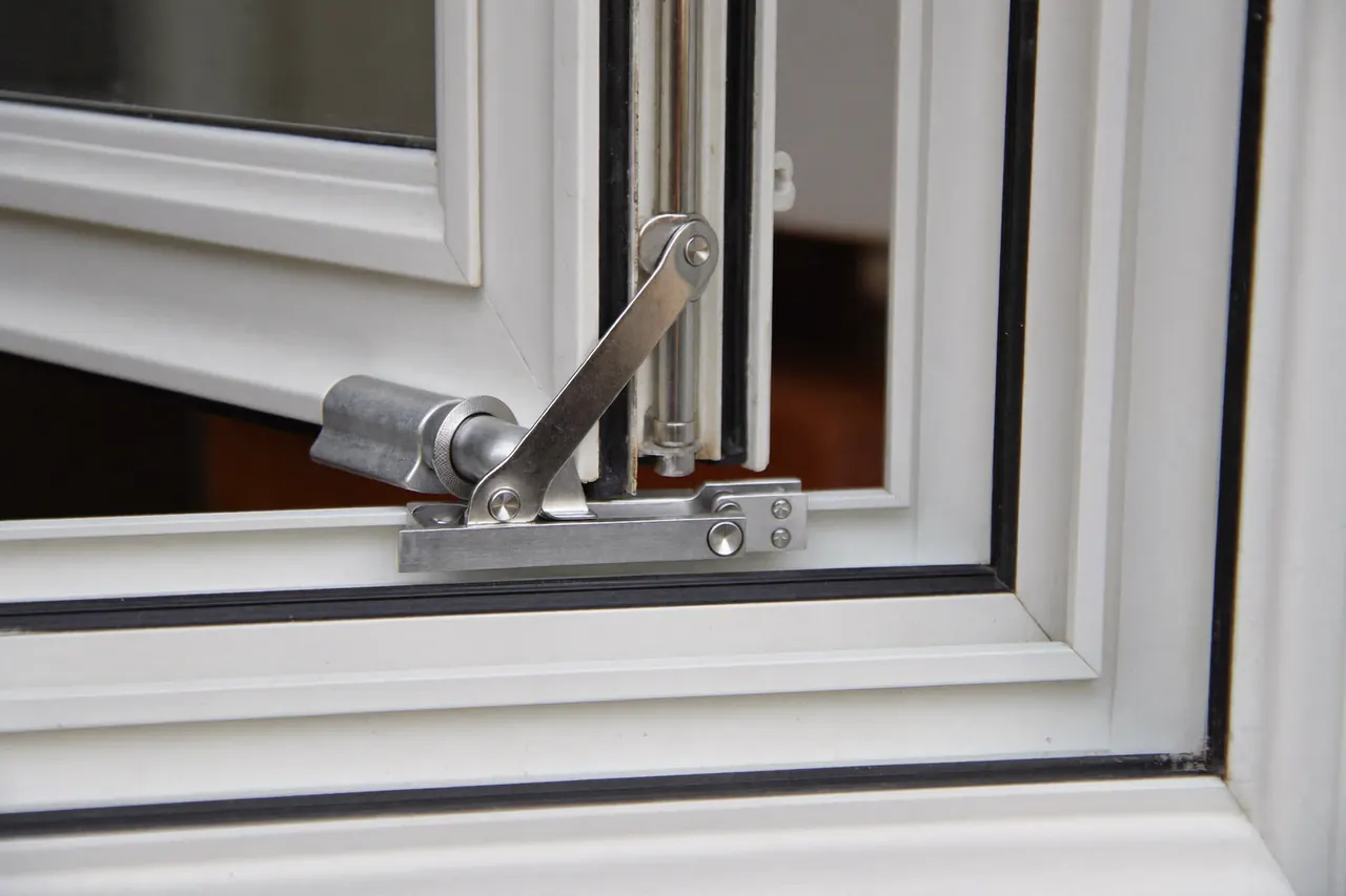 Close-up of a stainless friction stay hinge on an open casement window